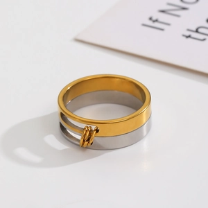Detail of two-tone stainless steel wide ring with hollow track and three movable gold beads