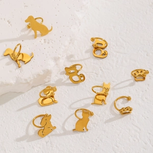 Nahaufnahme goldener Edelstahl-Ohrclips mit Katzen- und Hundepfoten auf weißem Stein