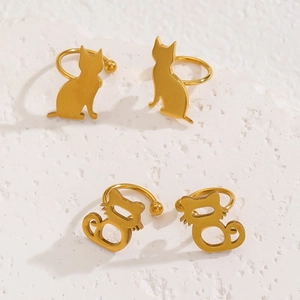 Detailansicht goldener Katzen-Ohrclips auf einem weißen strukturierten Steinuntergrund