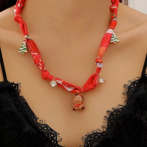 Gros plan d'un collier en soie rouge avec breloques de renne et sapin de Noël émaillé