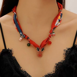 Détail d'un collier en soie avec pendentifs de Noël, élan, sapin et perles colorées