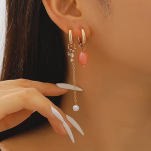 Detailed shot of asymmetric earrings with pink heart charms and elegant white faux pearls
