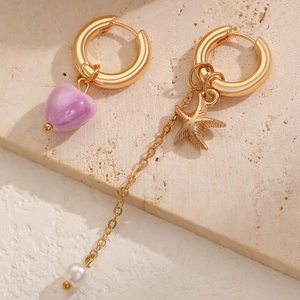 Detail of asymmetric gold earrings with purple marble heart and starfish pearl charms