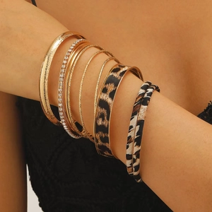 Gedetailleerd zicht op gelaagde luipaardprint leren armbanden met gouden ringen en kristal