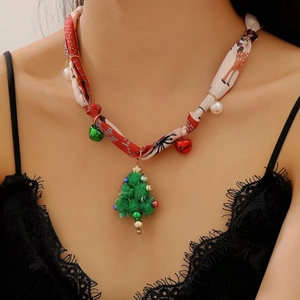 Détail d'un collier de Noël avec pendentif sapin, ruban en soie rouge et petits grelots