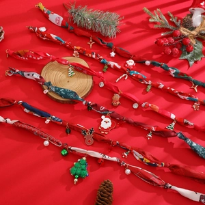 Chouchous de Noël en soie avec pendentifs renne et père noël sur un fond rouge festif