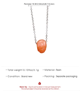 Detail van oranje schedelhanger met zilveren ketting en productspecificaties in beeld