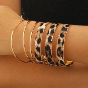 Macro-opname van gelaagde armbanden met luipaardprint en goudkleurige metalen details