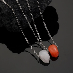 Collana gotica con teschio in pietra traslucida e catena d'argento su roccia nera