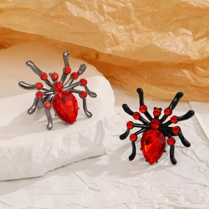 Detailed macro view of two Gothic spider rings with red rhinestones on a textured rock