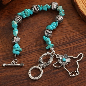 Detail of vintage turquoise stone bracelet with western bull head and flower charms