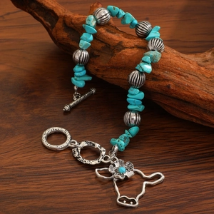 Close-up of bohemian turquoise beaded bracelet with a silver bull head charm on wood