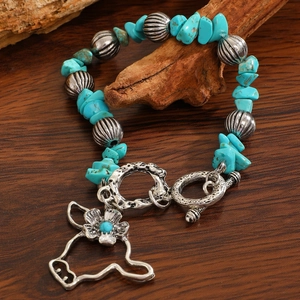 Macro shot of turquoise beaded bracelet with floral pendant and silver toggle clasp