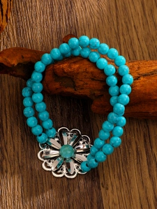 Detailed close-up of a vintage western turquoise beaded bracelet with silver flower charm