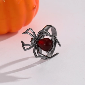Macro detail of gothic spider ring with deep red gemstone and pumpkin background
