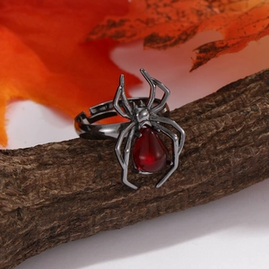 Gothic spider ring with large red crystal on wood bark and autumn maple leaf background