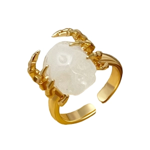 Detailopname van de gouden schedelklauw ring met doorschijnende steen en open ringband