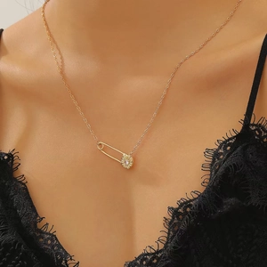 Detalle de collar de clip dorado con dije de margarita usado por modelo con encaje negro
