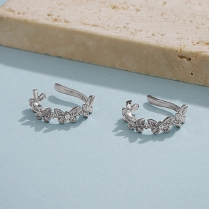 Detail of silver butterfly ear cuffs with sparkling cubic zirconia on a minimalist stone base