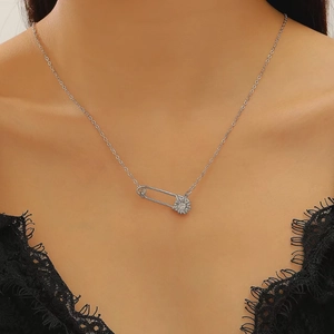 Detalle del collar con colgante de margarita y clip plateado usado con ropa de encaje