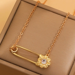 Collar de clip dorado con colgante de margarita y circón sobre joyero de cuero