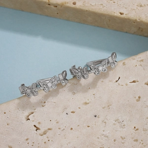 Detailed macro view of silver butterfly clip earrings with sparkling zircon inlay