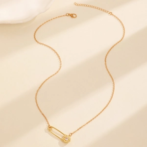 Detalle del collar de clip dorado con un colgante de flor de circón sobre superficie beige