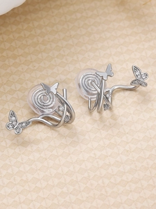 Detailed macro view of silver butterfly ear clips with zircon inlay and silicone pads