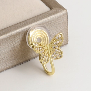 Macro shot of gold butterfly ear clip with sparkling cubic zirconia on a gift box
