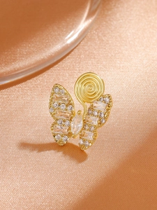 Macro detail of gold butterfly clip earring with sparkling cubic zirconia on satin