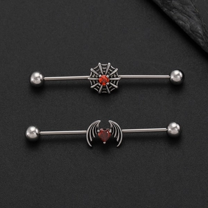 Detail of gothic spider web and red heart bat wing industrial barbell piercings