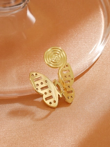 Detailed view of golden butterfly ear clip with zircon stones on soft silk fabric