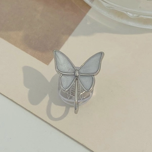 Macro shot of silver zircon butterfly clip earring on beige textured background