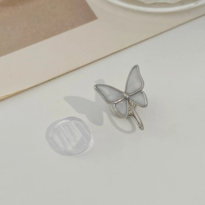 Close-up of zircon butterfly clip earring with comfortable silicone pad on minimalist surface