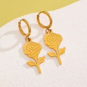 Detail of 18k gold plated flower earrings with rose pendant on textured stone base