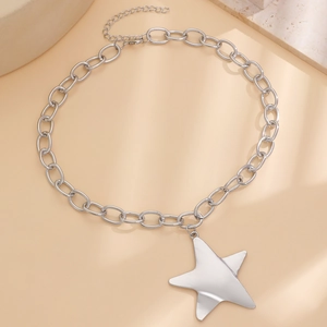 Collana a catena spessa in argento lucido con grande ciondolo a stella su fondo beige