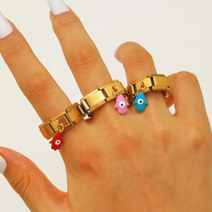 Detailansicht goldener modularer Gliederringe mit Hamsa-Hand und Bösem Blick Anhängern auf Weiß