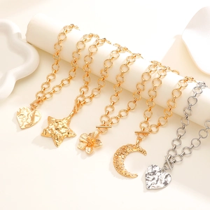 Dettaglio di collane oro e argento con ciondoli a stella e cuore e chiusura a levetta