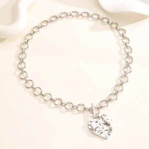 Dettaglio di un ciondolo a cuore in argento con trama martellata e chiusura a T