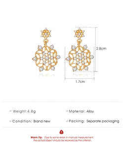 Detailed view of gold snowflake earrings showing dimensions 2.8cm by 1.7cm and alloy material