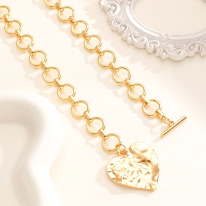 Primo piano della collana dorata con ciondolo a cuore martellato e chiusura a T