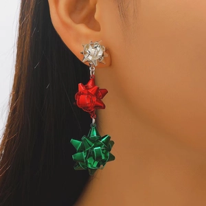 Dettaglio di orecchini festivi a strati con fiocchi color argento, rosso e verde