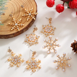 Elegant gold snowflake earrings with sparkling diamonds and pearls on winter wood decor