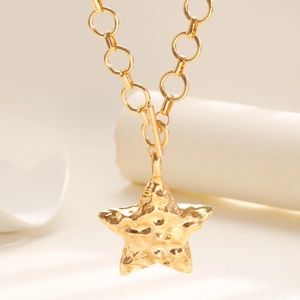 Dettaglio della collana con chiusura a T dorata e grande pendente a stella martellata
