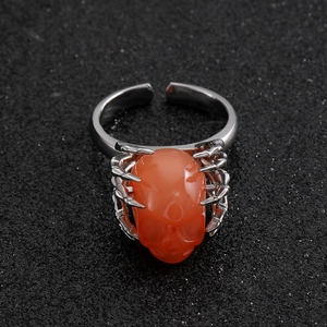 Gothic verstelbare ring met een oranje schedelkop en zilveren skelethand accenten