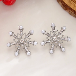 Macro shot of silver snowflake earrings with crystal rhinestones and white pearls