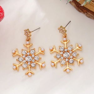 Detailed view of gold snowflake earrings with rhinestones and pearls on Christmas decor