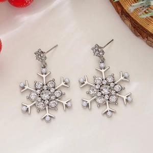 Detail of silver snowflake earrings with rhinestones and pearls on a festive background