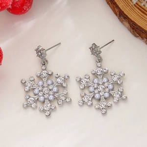 Macro detail of snowflake earrings with rhinestones and white pearls on festive background