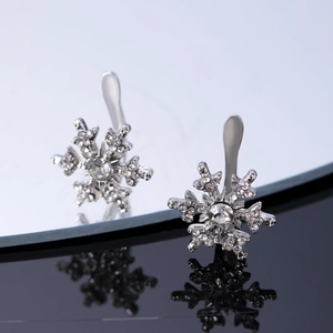 Macro view of silver snowflake earrings with sparkling zircons on reflective surface